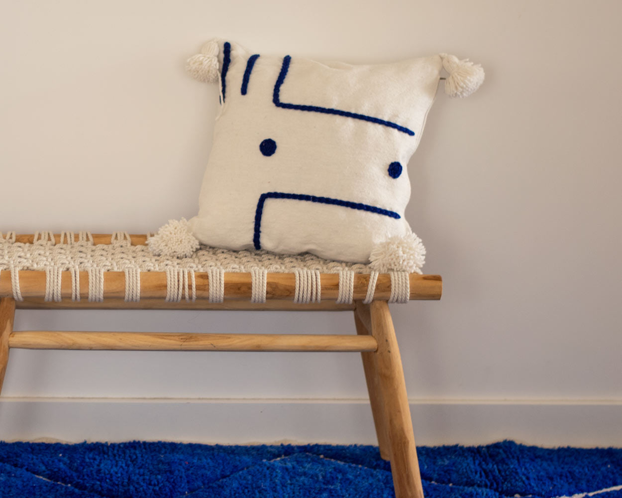 White cushion cover blue embroidered shapes