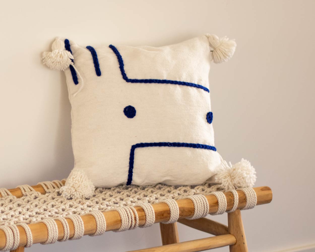 White cushion cover blue embroidered shapes